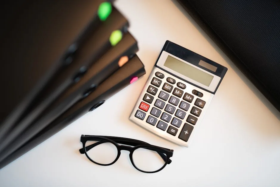 Calculator with glasses and folders on an office desk. Perfect for finance and accounting themes.